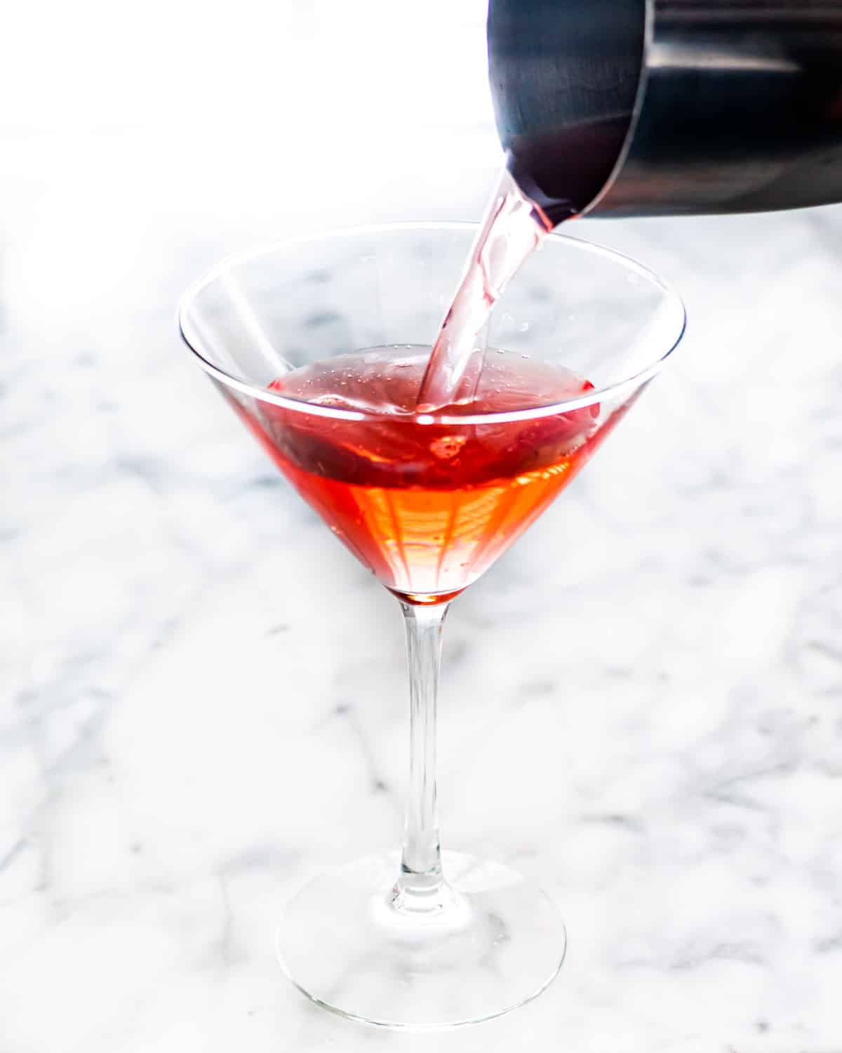 pouring a cosmopolitan drink in a martini glass