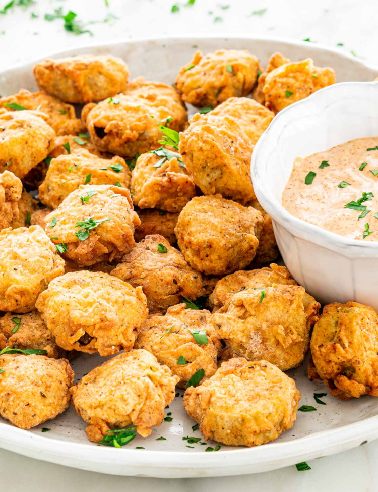side view shot of a plate full of fried pickles with a side of chipotle aioli