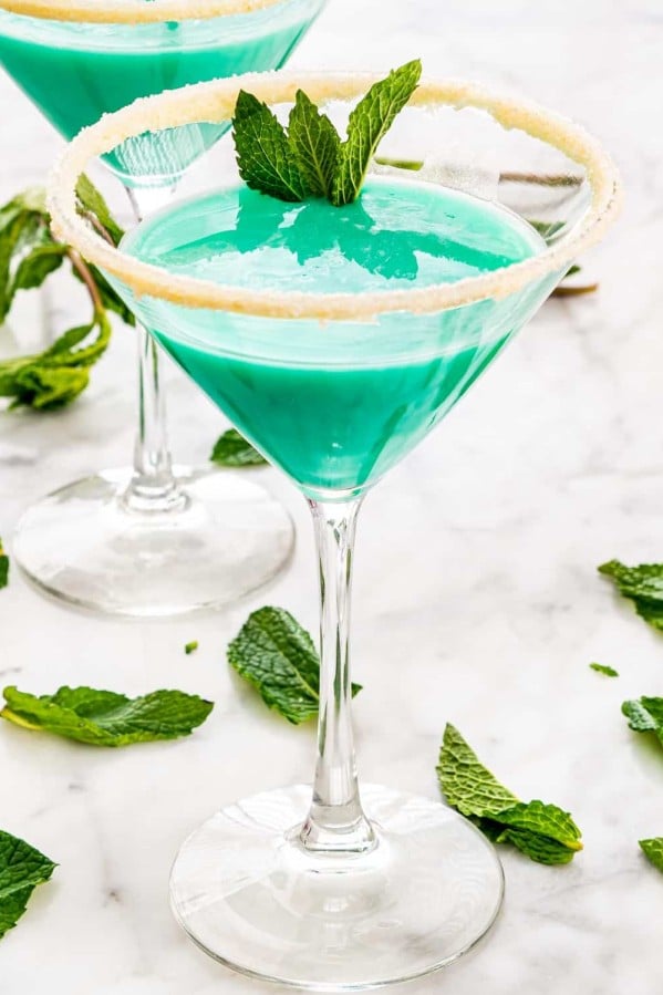 bright green grasshopper cocktails in martini glasses with white chocolate sugar rims, garnished with mint