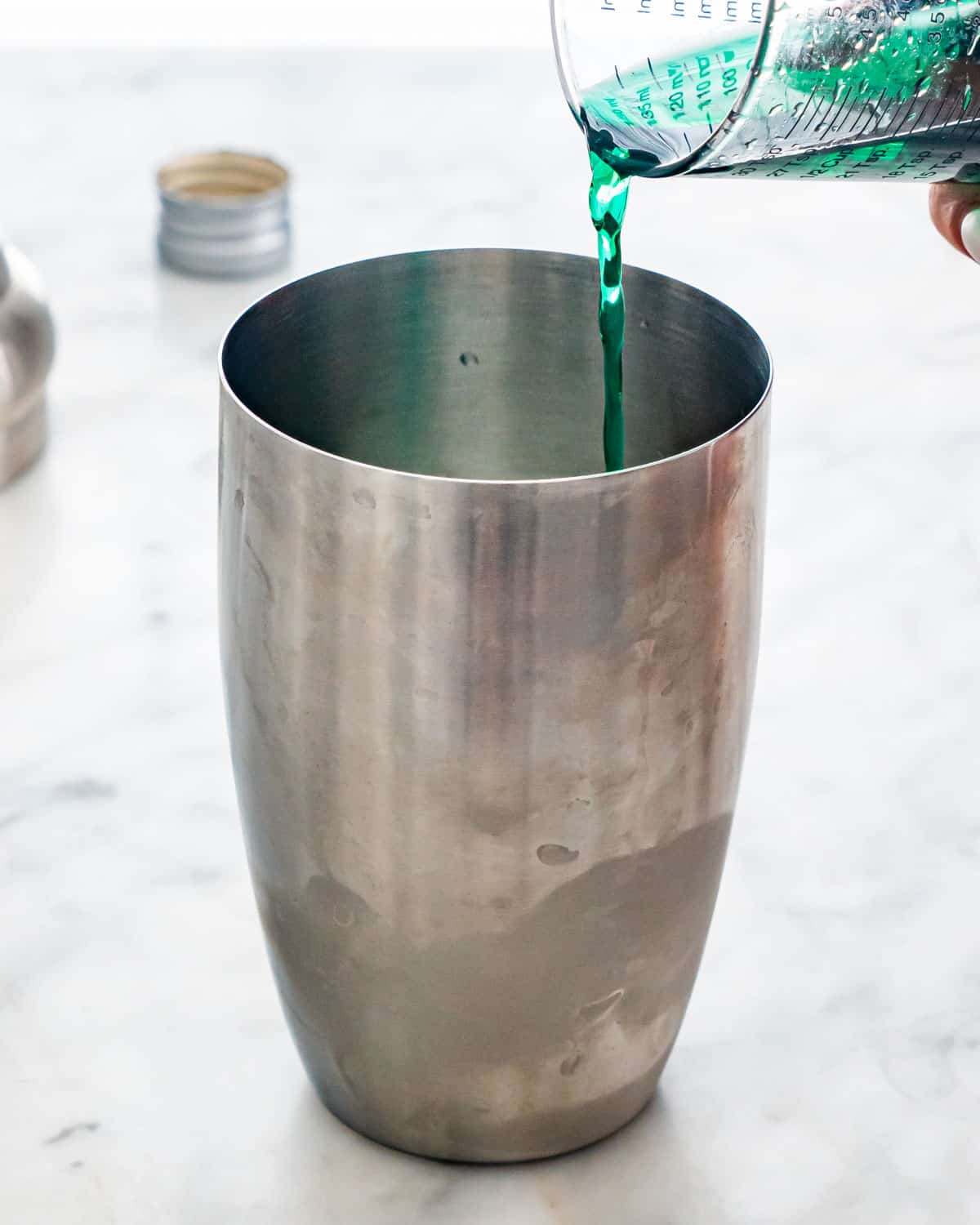 pouring creme de menthe in a cocktail shaker