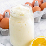 a jar of homemade mayonnaise with a lemon slice and carton of eggs next to it