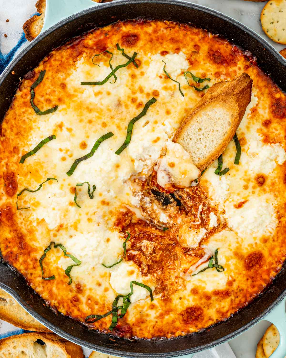 overhead shot of lasagna dip in a skillet with a piece of toast