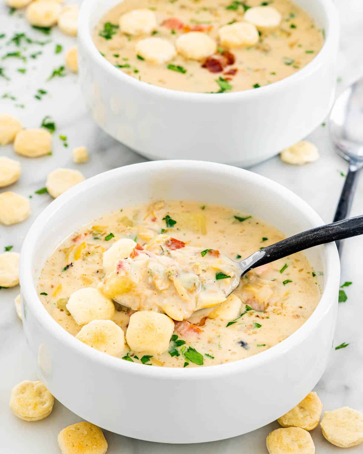 two white bowls filled with clam chowder and topped with oyster crackers