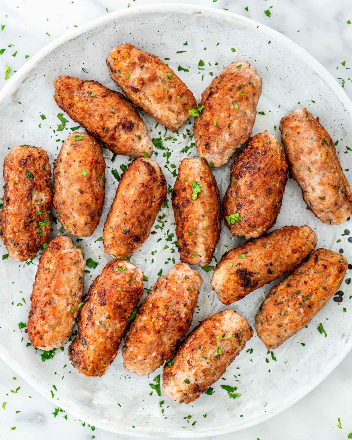 overhead shots of pork sausages in a plate garnished with parsley