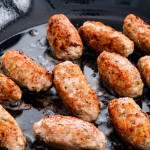 side view shot of pork sausages in a skillet