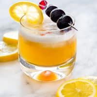 a whiskey sour garnished with lemon slices and bourbon cherries