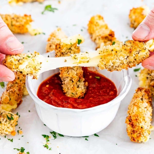 hands pulling apart a mozzarella stick with the rest in the background
