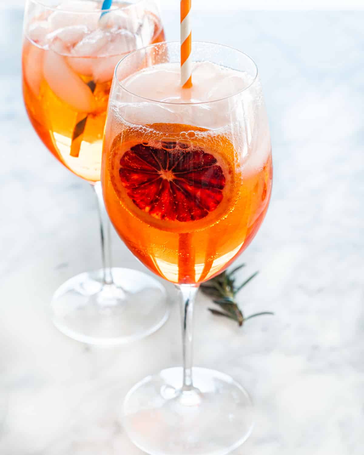 two wine glasses with aperol spritz garnished with blood orange wheels