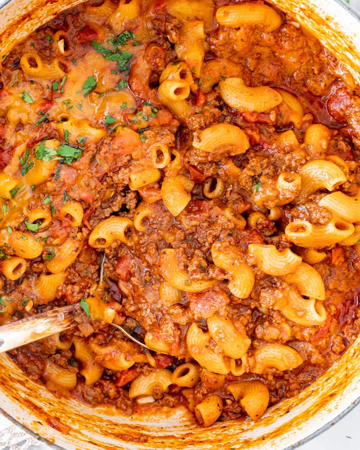 closeup overhead shot of american goulash in a dutch oven with a ladle inside
