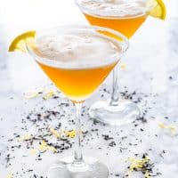 side shot of 2 martini glasses filled with earl grey martini and garnished with lemon wedges