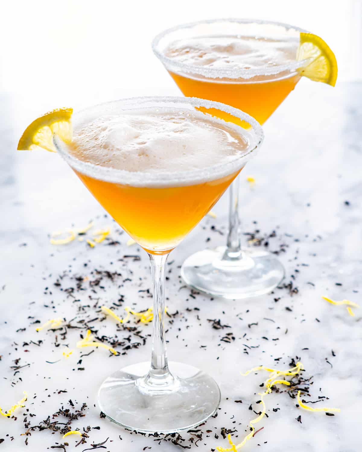 side shot of 2 martini glasses filled with earl grey martini and garnished with lemon wedges