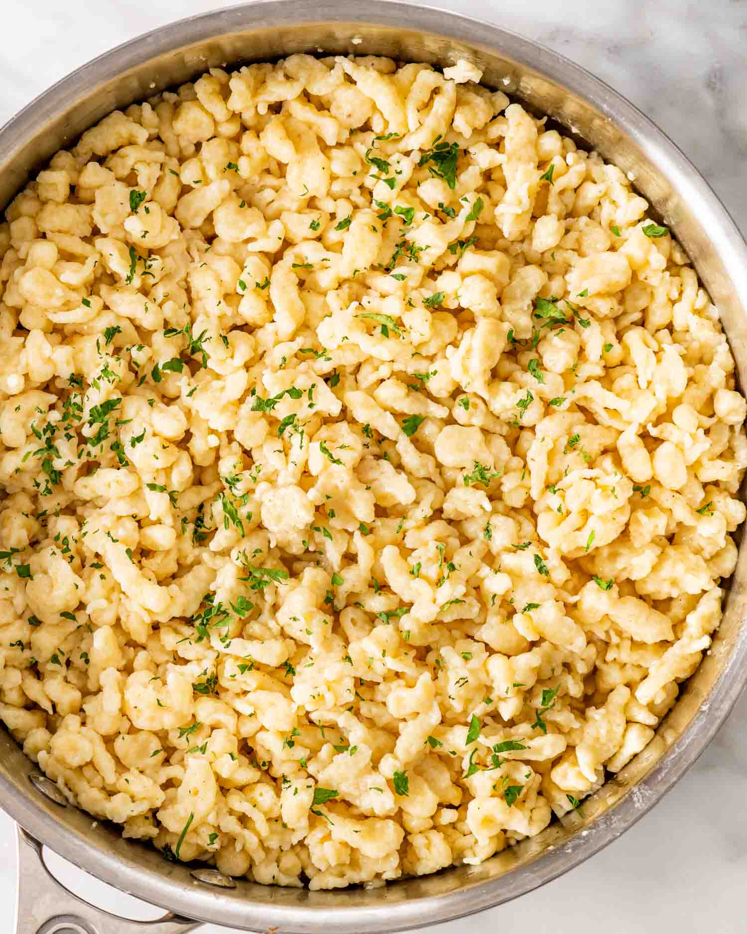 freshly sauteed spaetzle in a skillet garnished with a bit of fresh parsley.