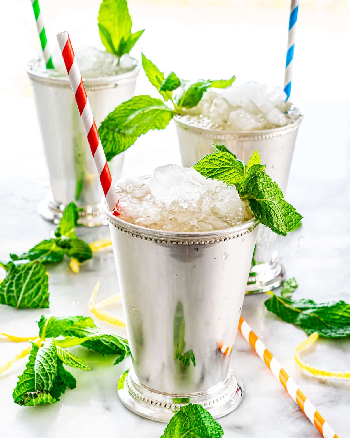 side shot of 3 mint julep cups filled with mint julep, crushed ice and lots of fresh mint