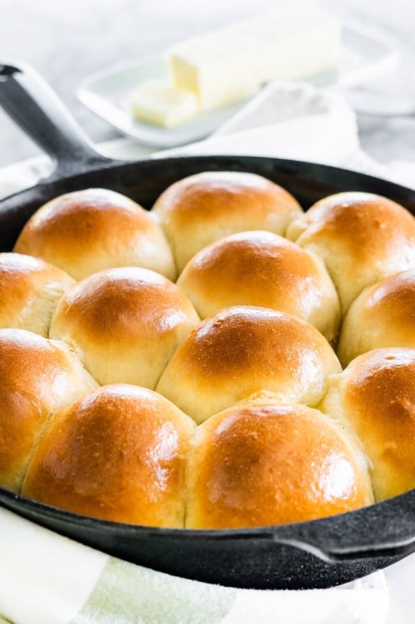 side shot of freshly baked quick yeast dinner rolls in a skillet brushed with butter