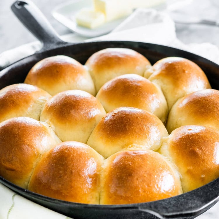 side shot of freshly baked quick yeast dinner rolls in a skillet brushed with butter