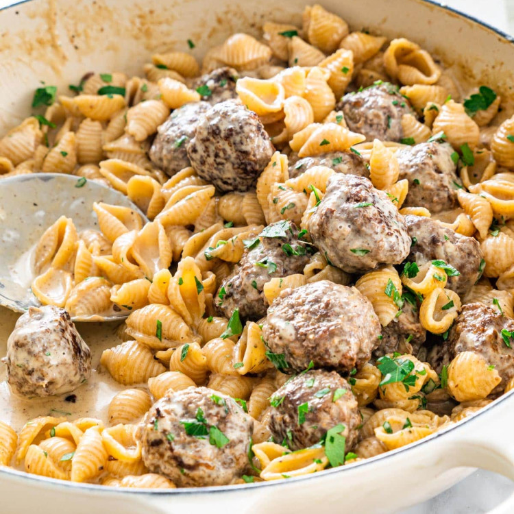 side close up shot of swedish meatball pasta in a beige braised garnished with parsley