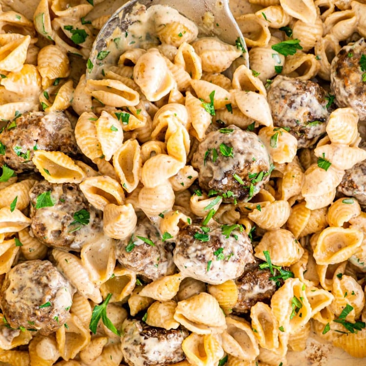 overhead close up shot of swedish meatball pasta in a beige braised garnished with parsley