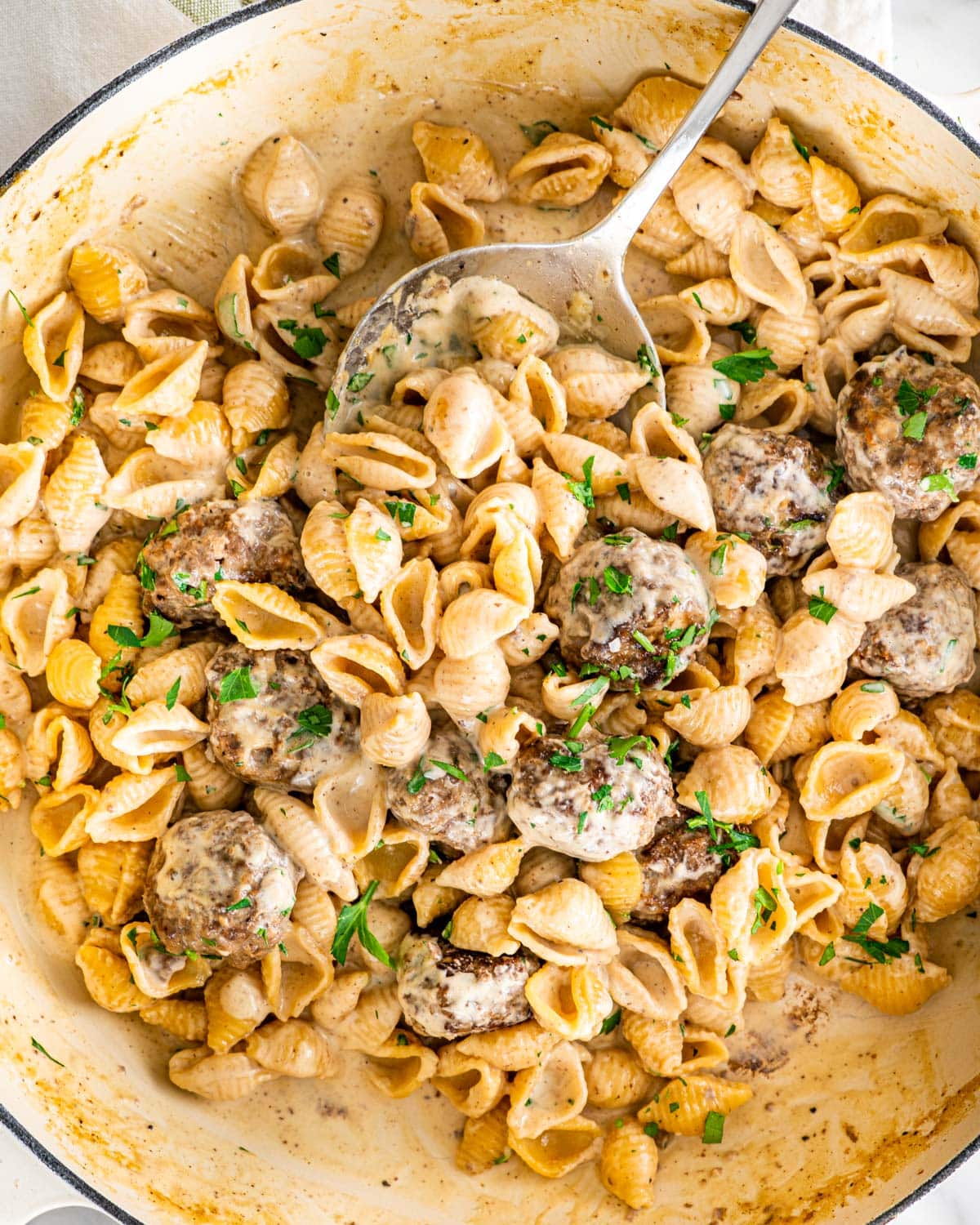 overhead shot of swedish meatball pasta in a beige braised garnished with parsley