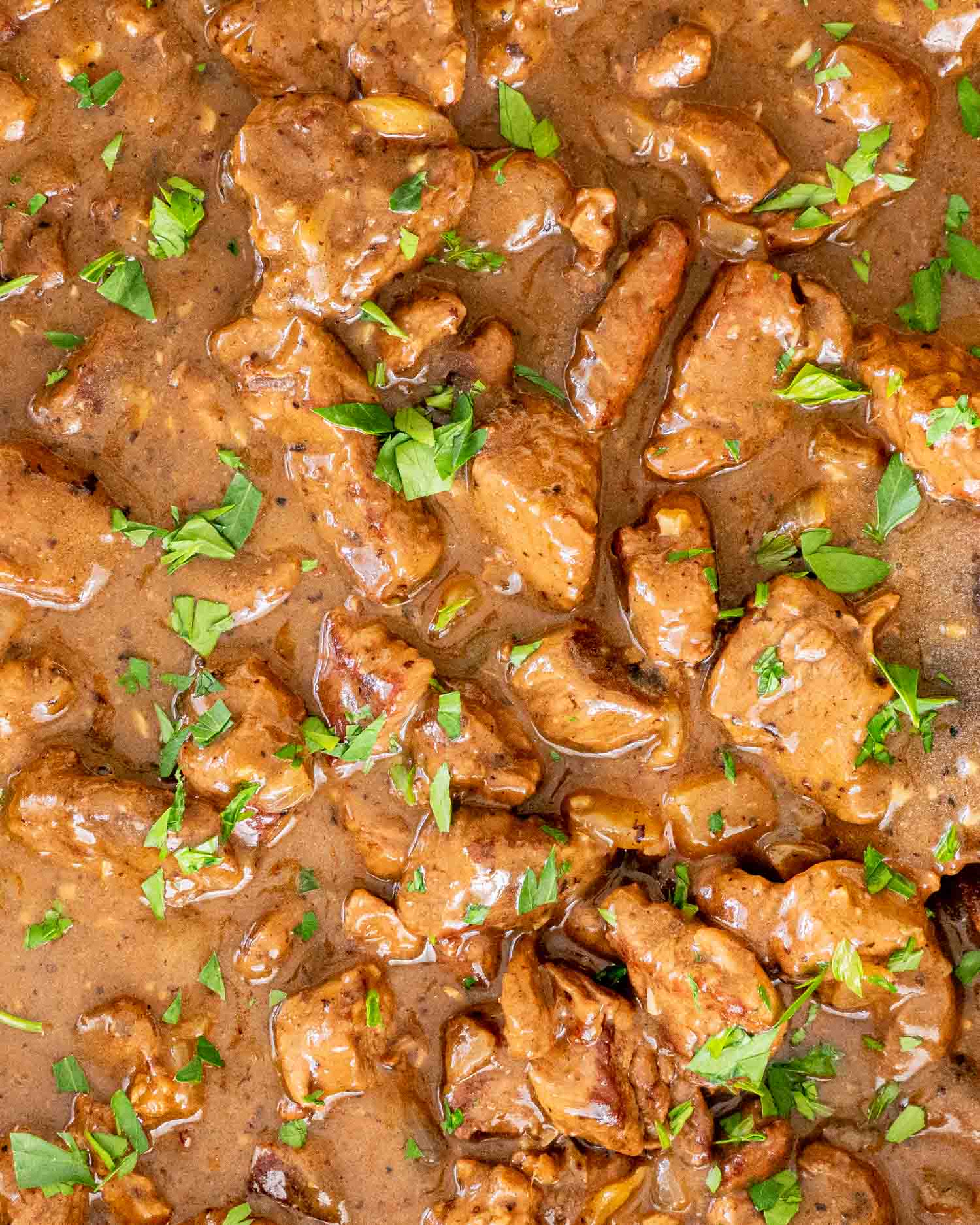 beef tips with gravy in a braiser garnished with parsley.