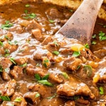 beef tips with gravy in a braiser garnished with parsley.