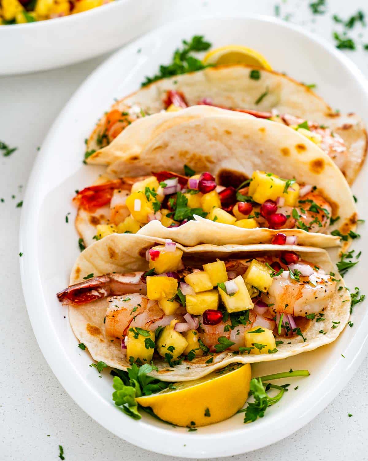 a plate full of shrimp tacos with pineapple salsa.