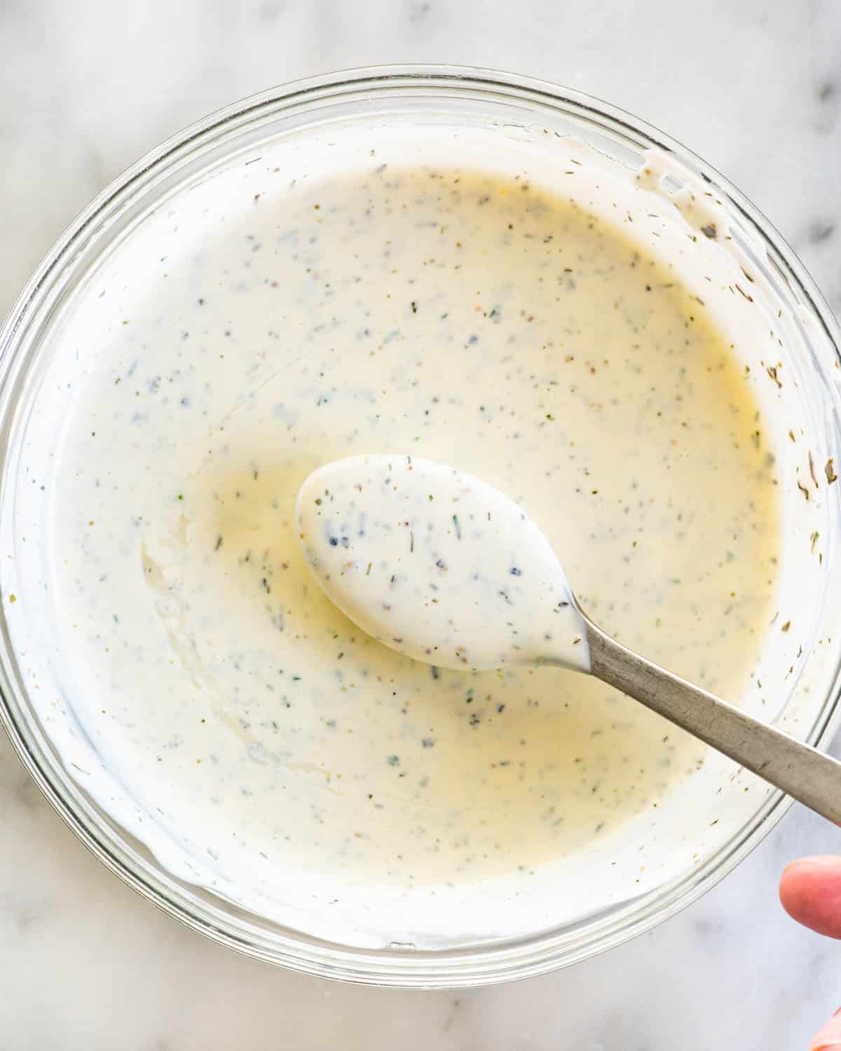 overhead shot of ranch dressing in a bowl with a spoon spooning some out