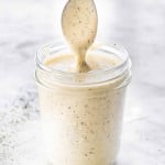 side view shot of a jar filled with homemade ranch dressing and a spoon lifting some up