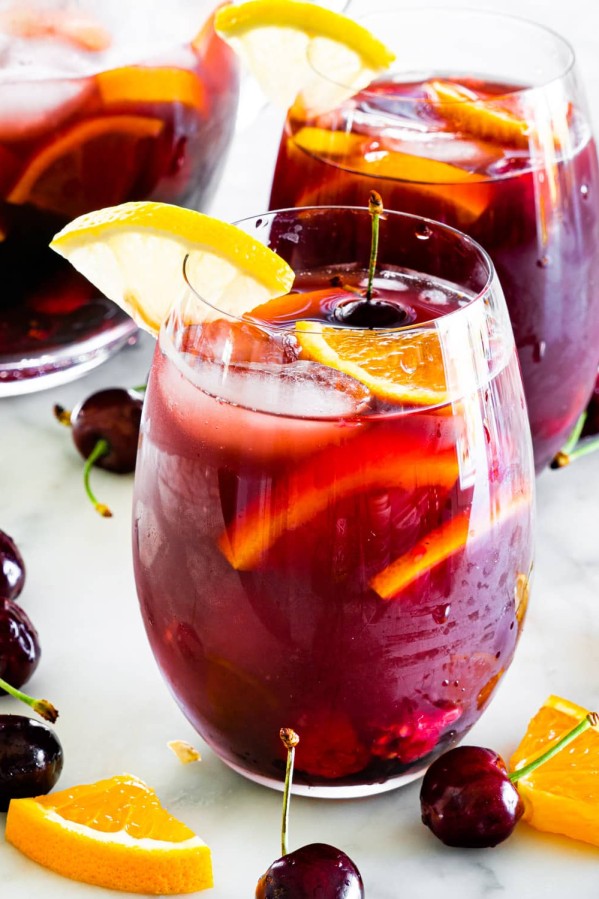 sideview shot of 2 glasses filled with red sangria and a pitcher in the background