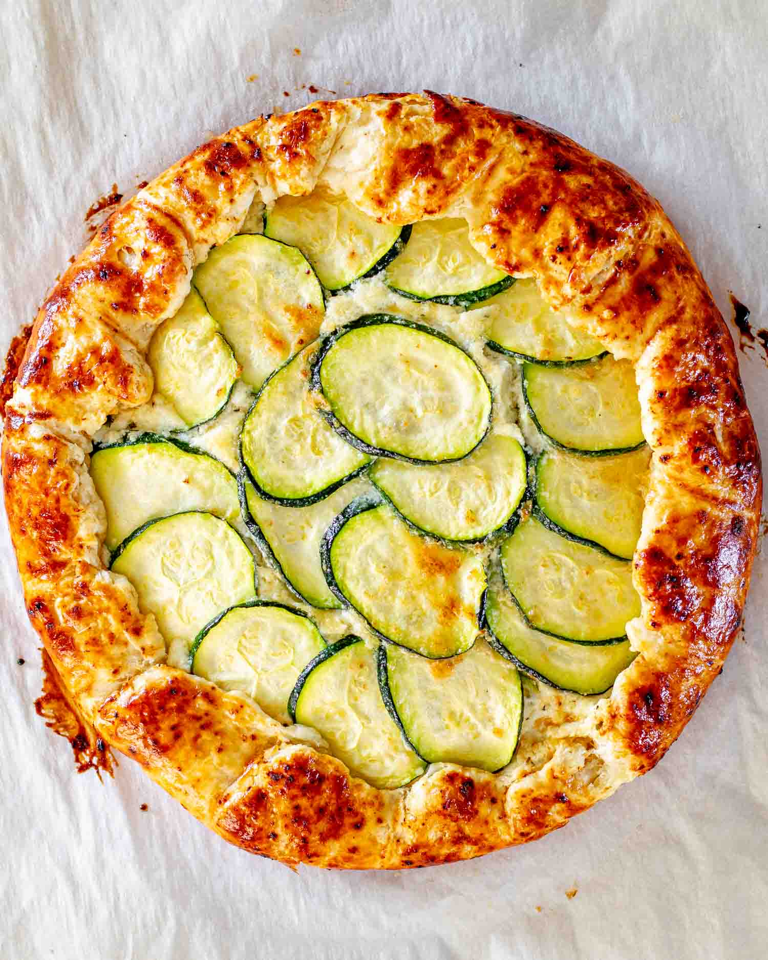 a fresh out of the oven zucchini ricotta galette on a baking sheet lined with parchment paper.