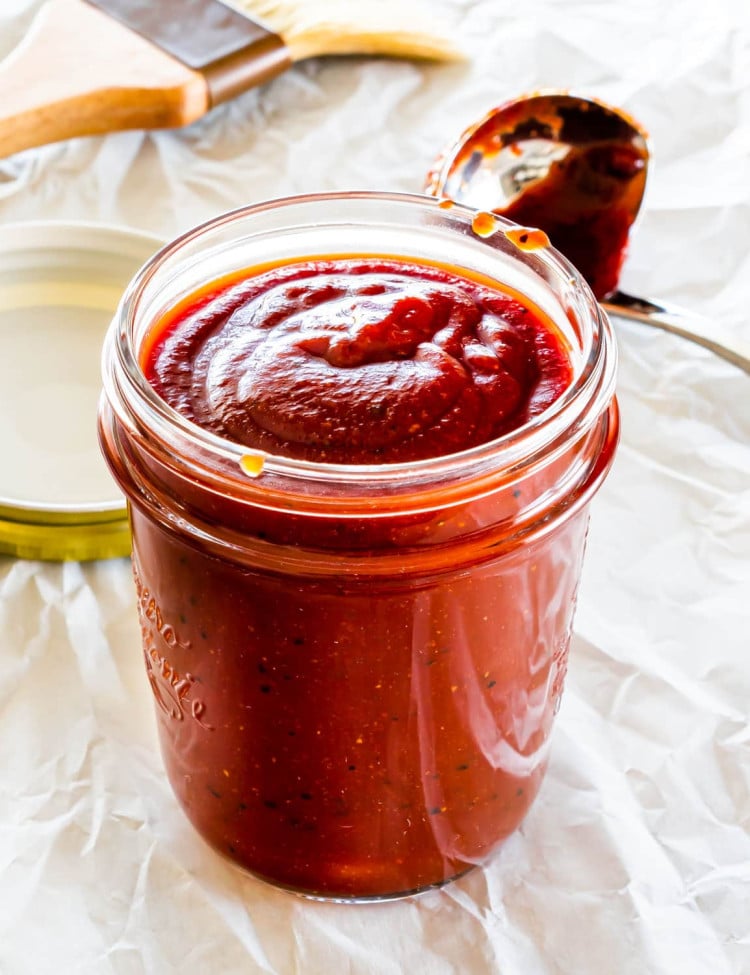 homemade bbq sauce in a jar with a ladle behind it