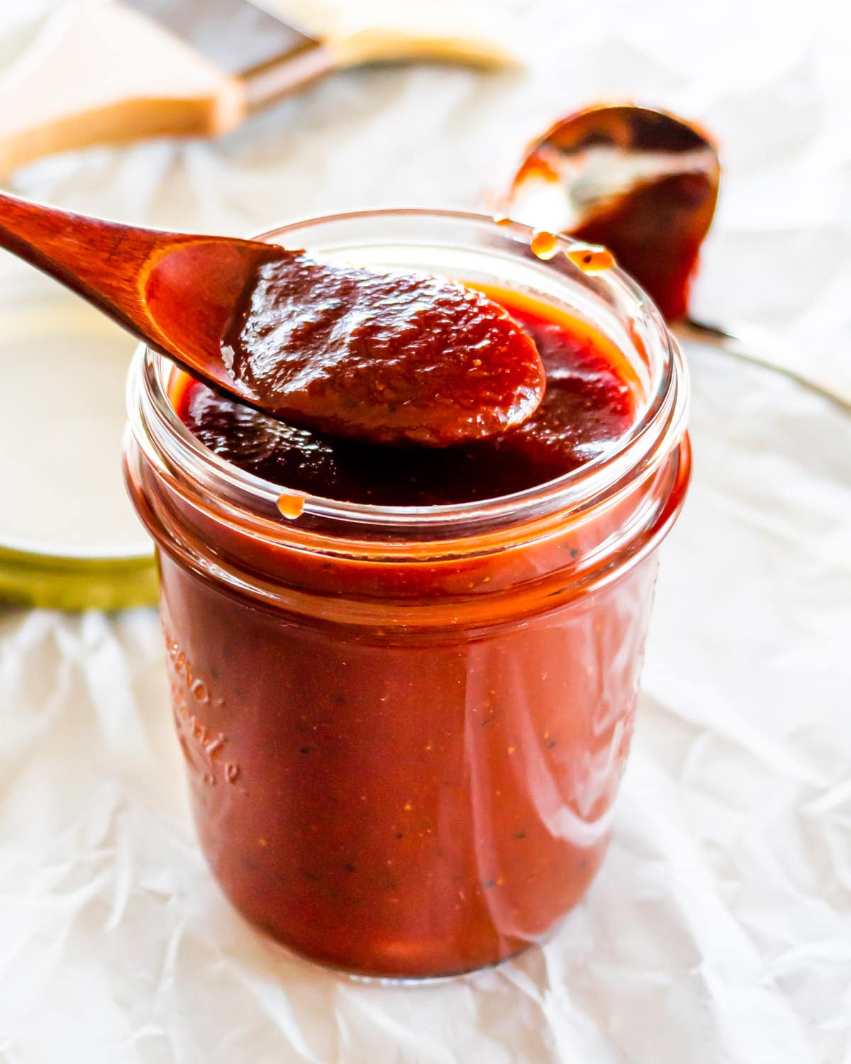 homemade bbq sauce in a jar with a wooden spoon in it