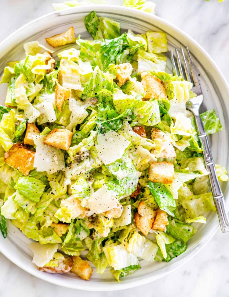 overhead shot of freshly made caesar salad on a plate with a fork in it