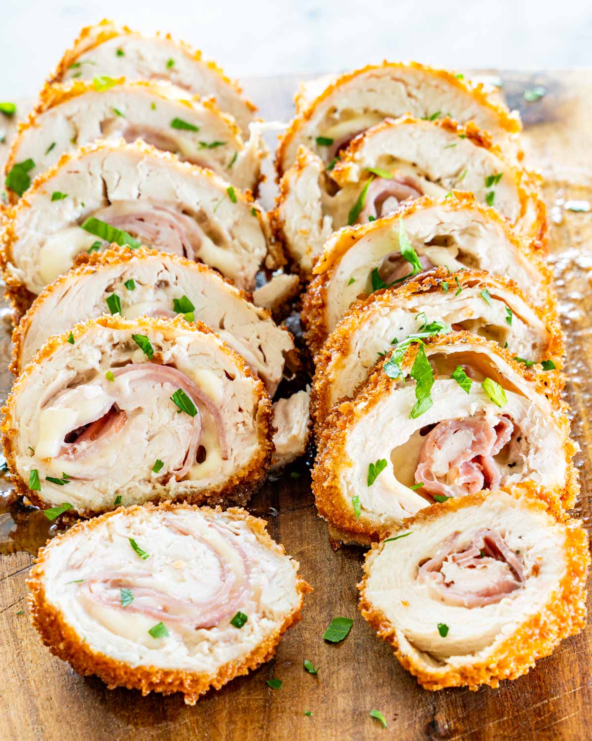 side view shot of 2 pieces of chicken cordon blue sliced on a cutting board.