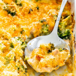 side view shot of chicken divan in a white casserole dish with a serving spoon in it