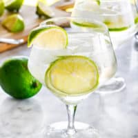 two gin and tonic glasses garnished with lime wedges