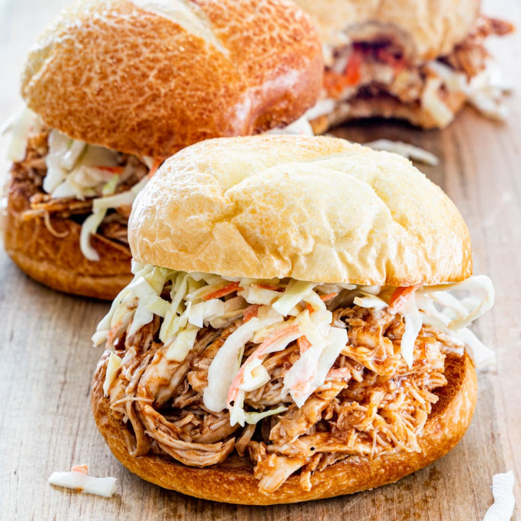 side view shot of a bbq pulled chicken sandwich with coleslaw on a cutting board