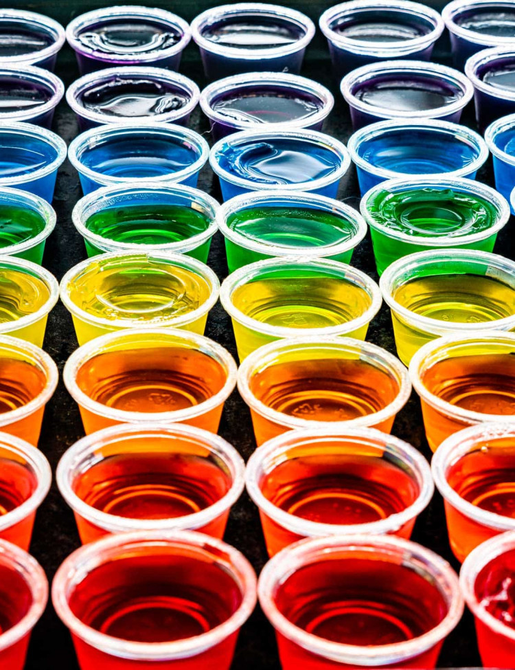 a rainbow of jello shots in small plastic cups