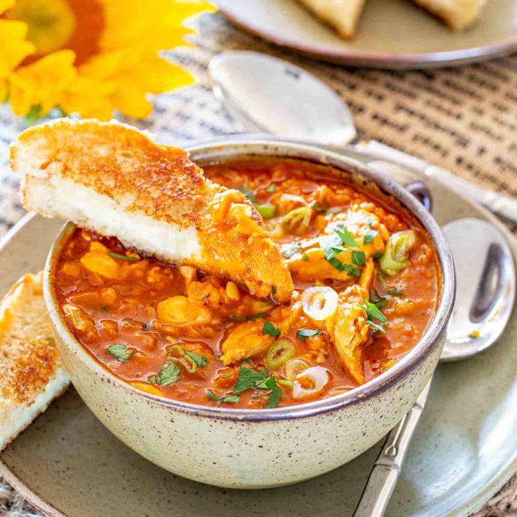 red lentil chicken soup garnished with parsley and green onions in a bowl along side some grilled cheese.