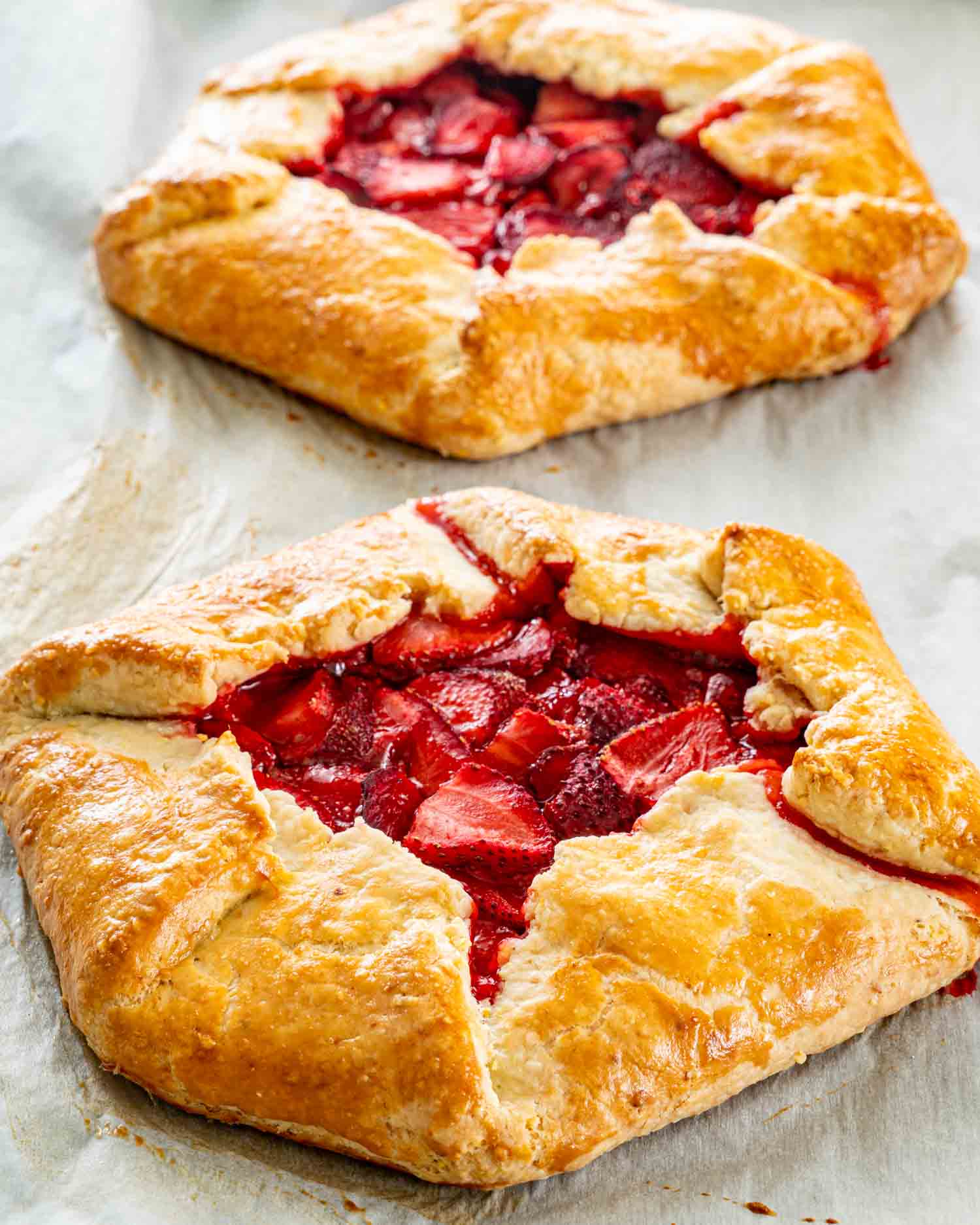 two strawberry galettes fresh out of the oven on a baking sheet lined with parchment paper.