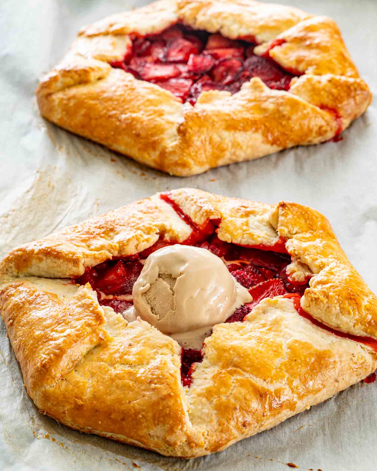 two strawberry galettes fresh out of the oven on a baking sheet lined with parchment paper.