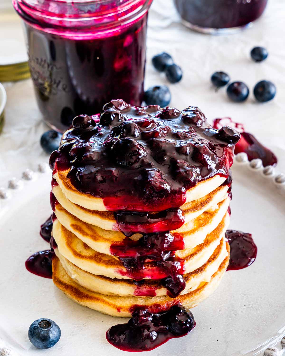 side view shot of a beautiful stack of pancakes loaded with homemade blueberry sauce