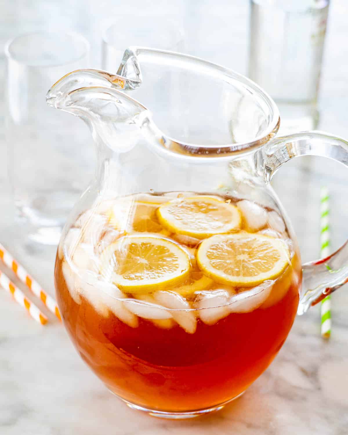 a boozy arnold palmer cocktail in a pitcher with lemon slices and ice