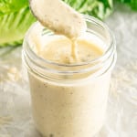 freshly made caesar salad dressing in a jar with a teaspoon inside.