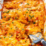 side view shot of king ranch chicken casserole fresh out of the oven and cut into slices with a couple slices missing and a black spatula inside