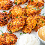 potato latkes garnished with parsley next to two little bowls with sour cream and applesauce