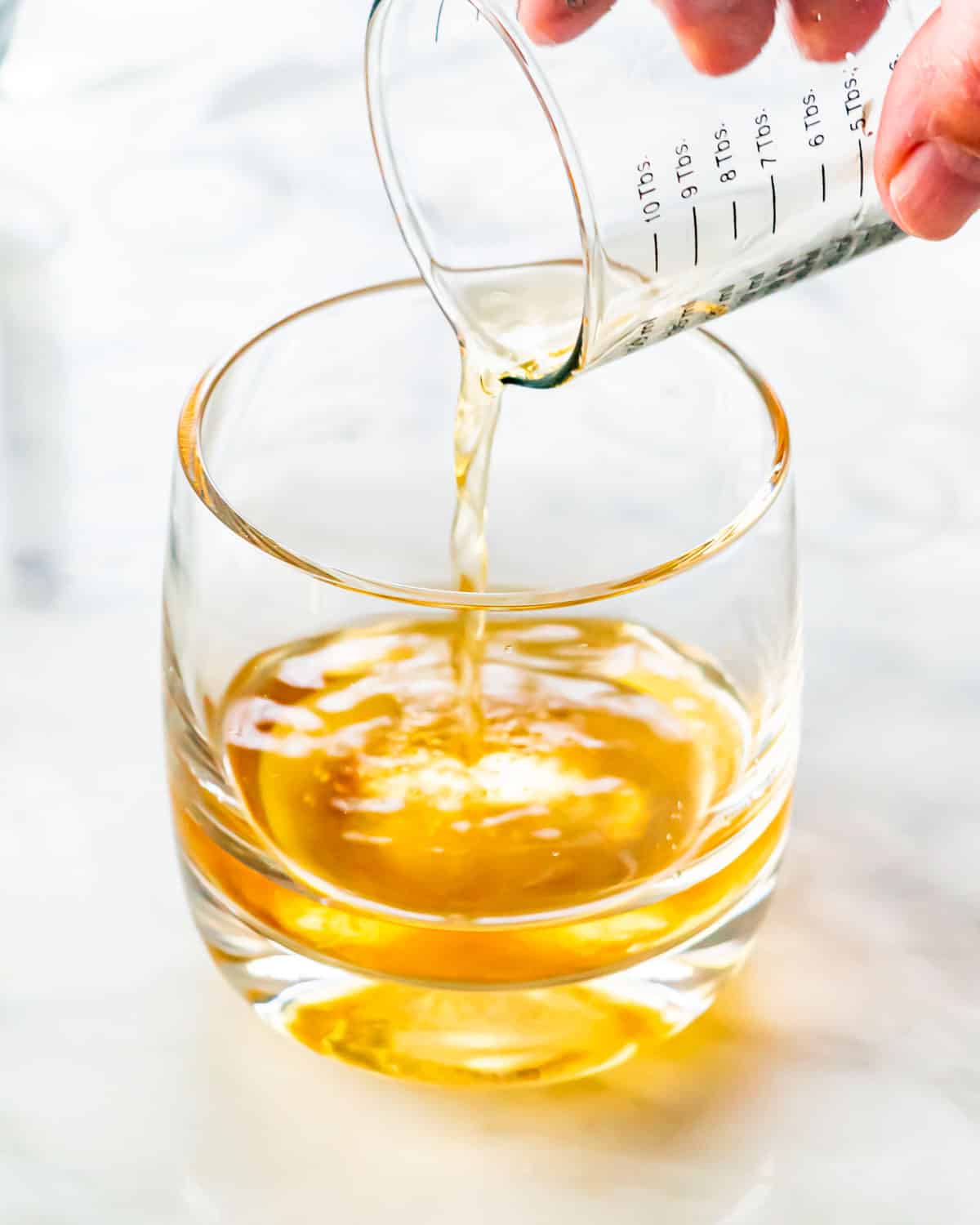 a hand pouring bourbon in a glass