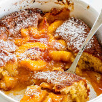 freshly made peach cobbler in a white oval baking dish.