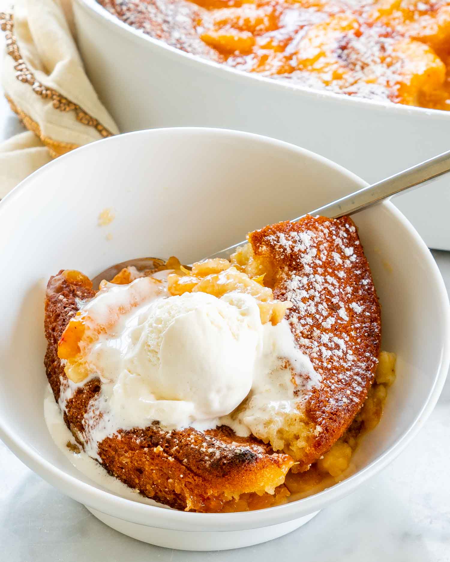 a serving of peach cobbler with a scoop of vanilla ice cream in a bowl.