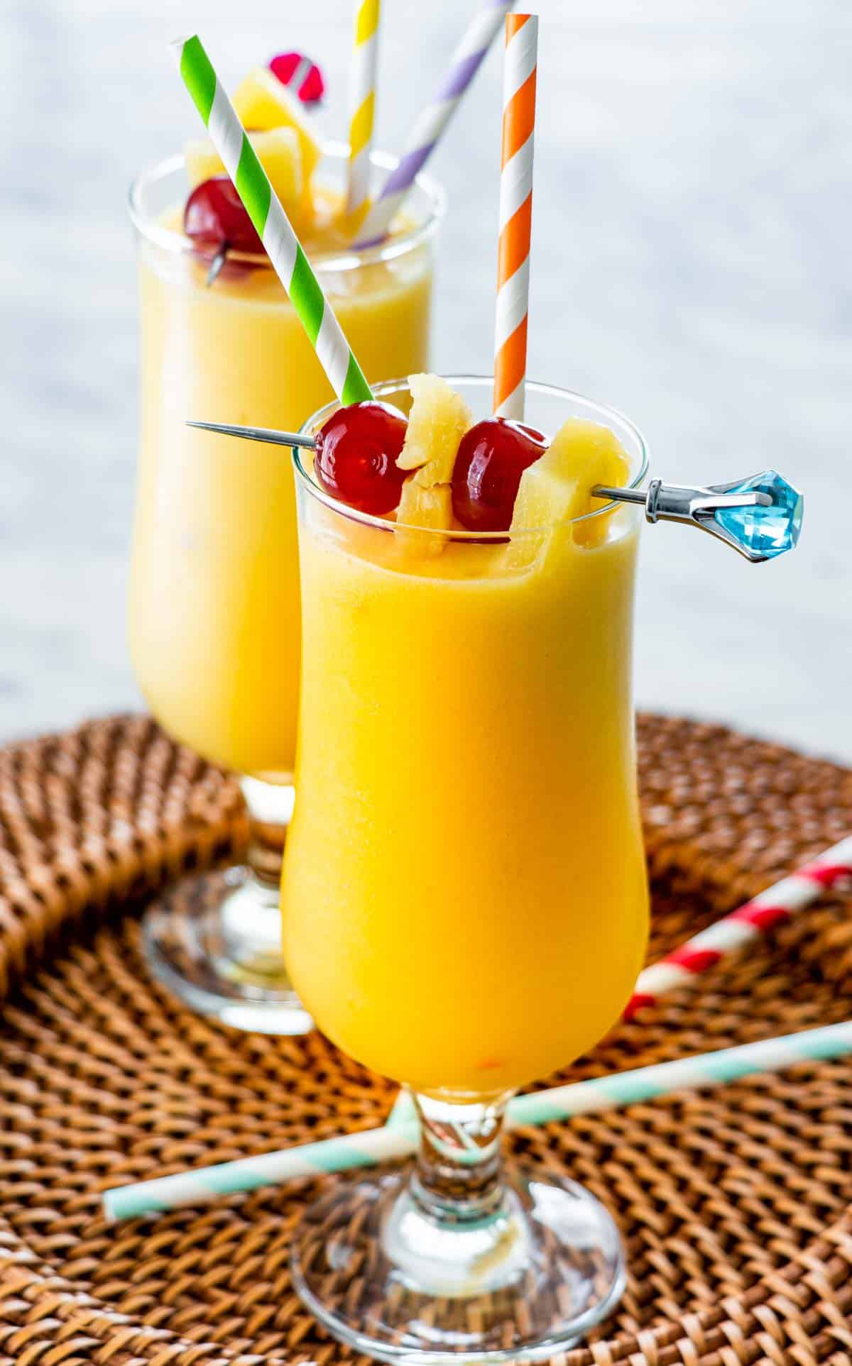 two glasses with Piña Colada and garnished with maraschino cherries and pineapple wedges