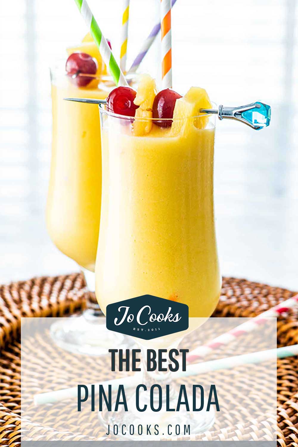 two glasses with Piña Colada and garnished with maraschino cherries and pineapple wedges